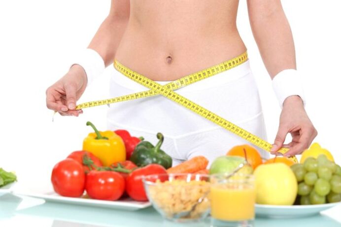girl measuring waist against the background of groceries